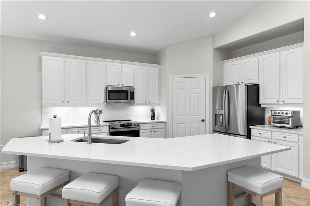 1286 Rialto Way, Unit 9202 Naples, FL 34114 - Photo 5 of 49 Bright, fully updated kitchen featuring brand-new quartz countertops, updated cabinetry, stainless steel appliances, recessed lighting, vaulted ceilings, and a spacious island.