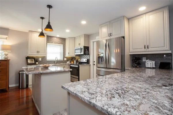 a kitchen with stainless steel appliances granite countertop a sink a stove a refrigerator a center island a stove and cabinets