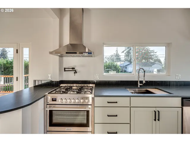 a kitchen with stainless steel appliances a stove a sink a counter space and a window