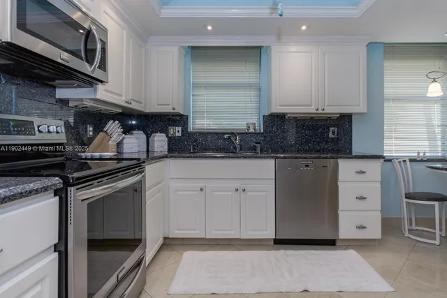 a kitchen with granite countertop a sink cabinets and stainless steel appliances