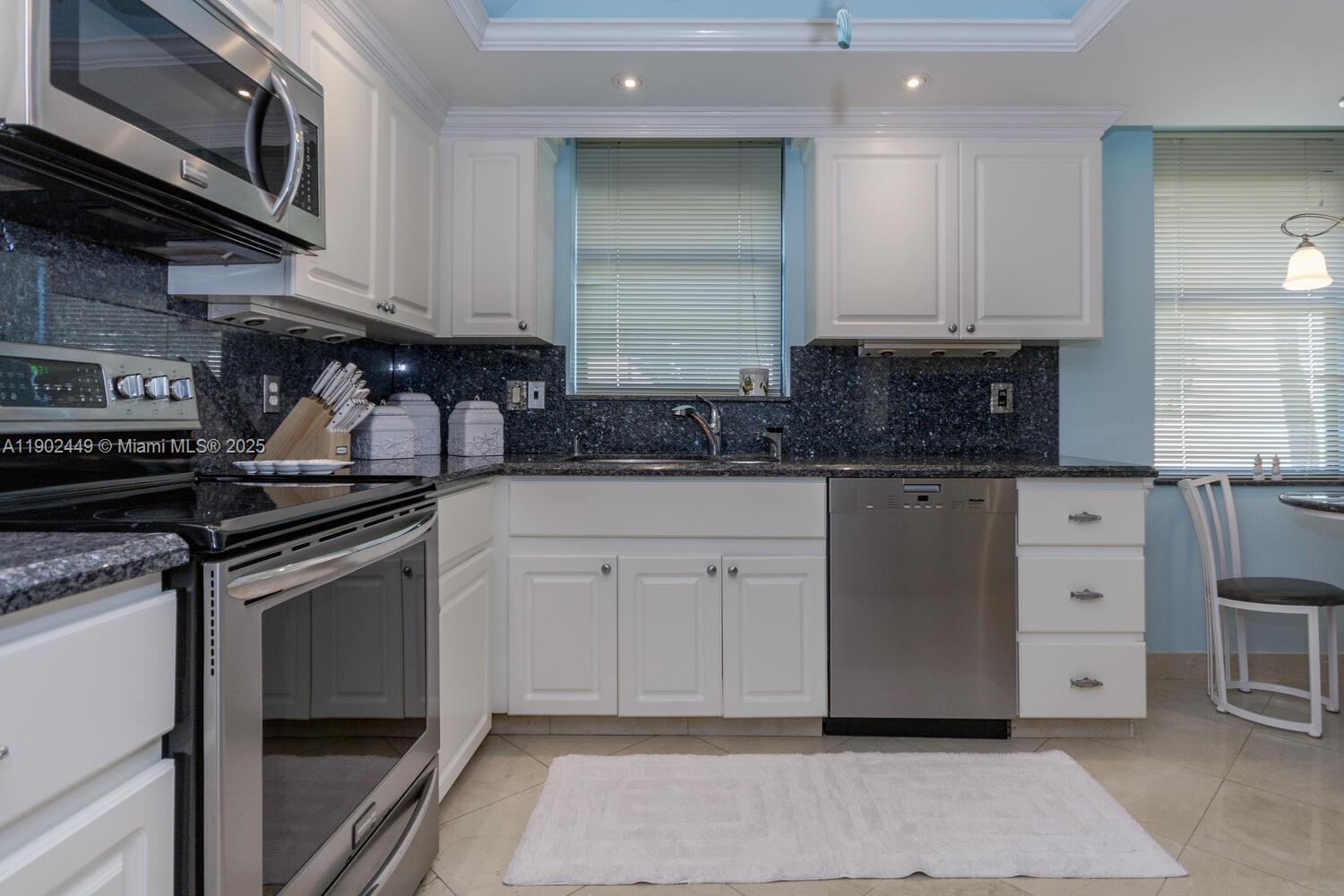 290 Celestial Way, Unit 2 Juno Beach, FL 33408 - Photo 15 of 40 a kitchen with granite countertop a sink cabinets and stainless steel appliances