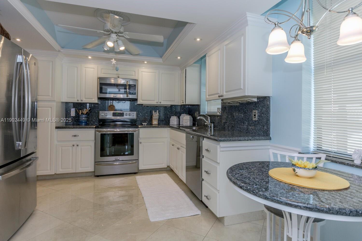 290 Celestial Way, Unit 2 Juno Beach, FL 33408 - Photo 16 of 40 a kitchen with stainless steel appliances granite countertop a sink a stove a refrigerator cabinets and a dining table