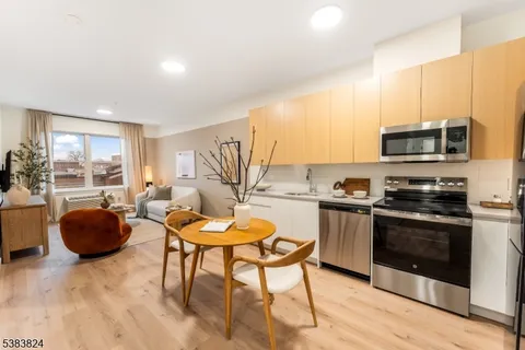 a kitchen with stainless steel appliances a stove a sink a microwave a dining table and chairs