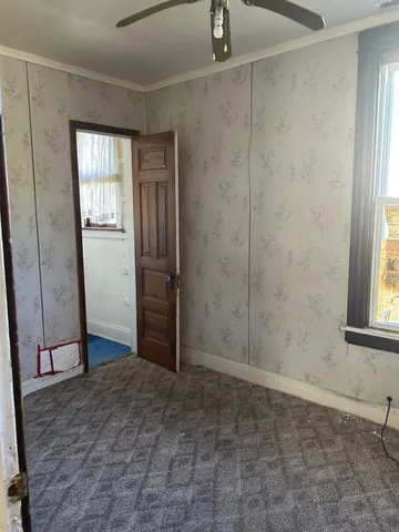 a view of an empty room with window and chandelier fan