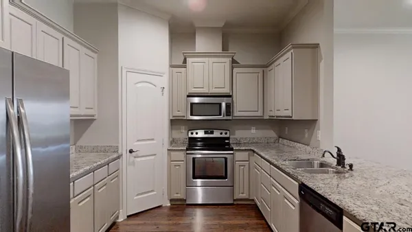 a kitchen with stainless steel appliances granite countertop a refrigerator a stove and a sink with wooden floor