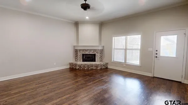 an empty room with wooden floor a fireplace and windows