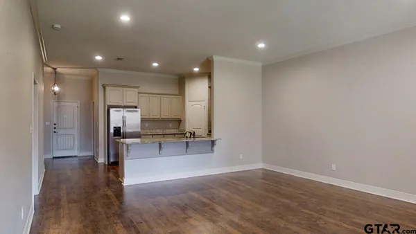 a view of kitchen with kitchen island granite countertop wooden floor stainless steel appliances and cabinets