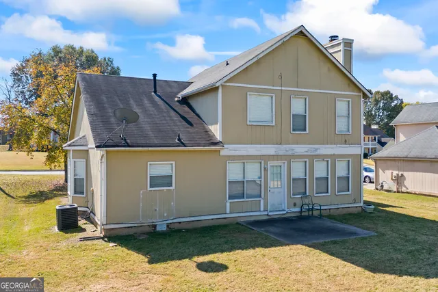 a view of a white house next to a yard with big trees