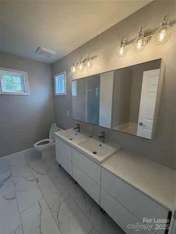 a bathroom with a double vanity sink toilet and mirror