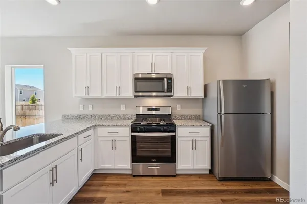 a kitchen with stainless steel appliances granite countertop a stove a sink and a microwave