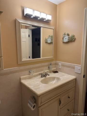 23 Notingham Circle, Unit 23 Peekskill, NY 10566 - Photo 9 of 12 Half bath featuring a wainscoted wall, tile walls, and vanity