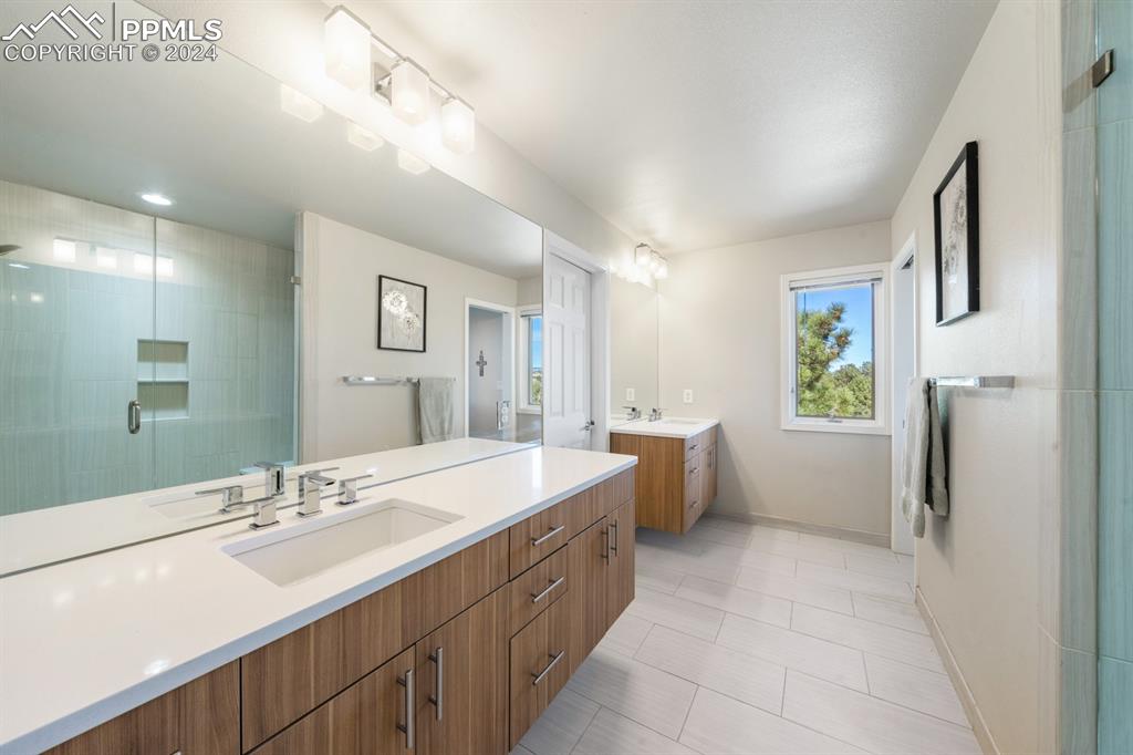 220 Preservation Way Colorado Springs, CO 80919 - Photo 16 of 39 a spacious bathroom with a double vanity sink a large mirror and a shower