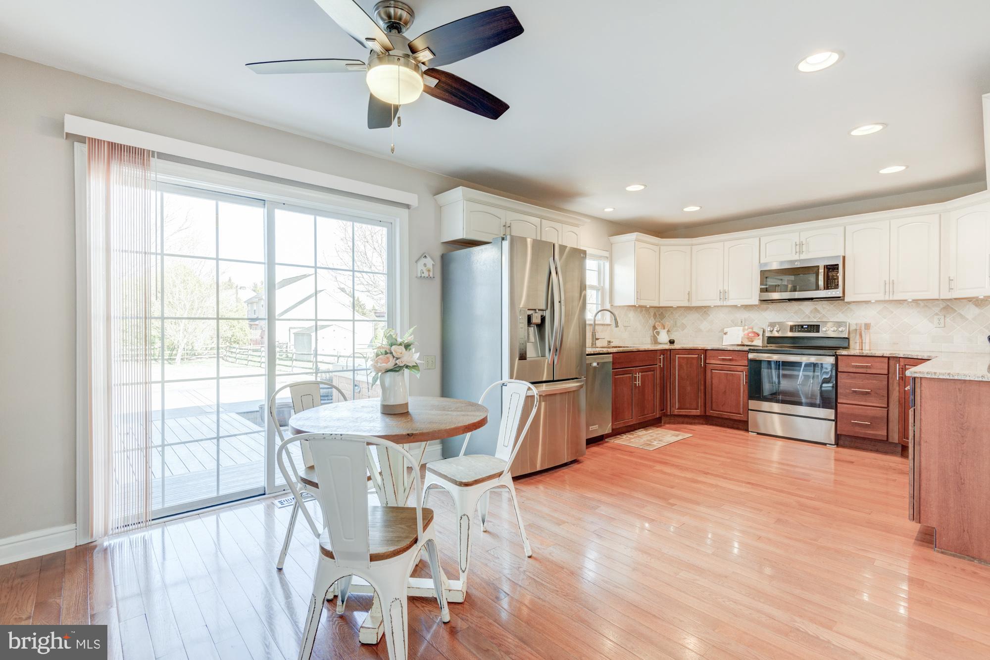 21 Oakview Drive Newark, DE 19702 - Photo 29 of 65 a kitchen with stainless steel appliances kitchen island granite countertop a refrigerator a sink dishwasher a dining table and chairs with wooden floor