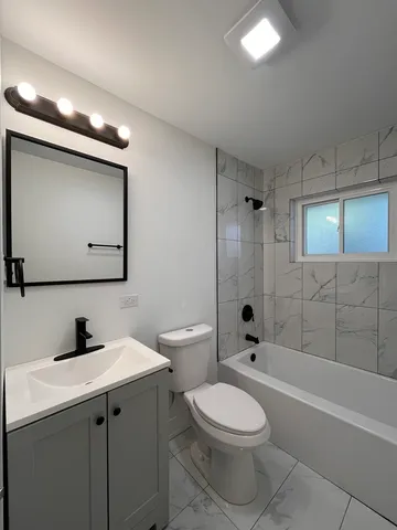 a bathroom with a toilet a sink a mirror a bathtub and vanity