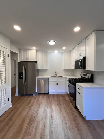 a large kitchen with stainless steel appliances granite countertop a large counter top a stove a refrigerator and a sink