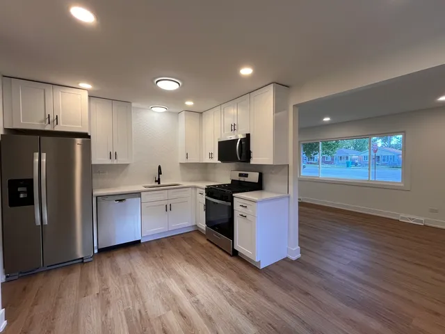 a kitchen with granite countertop a refrigerator stove top oven and sink