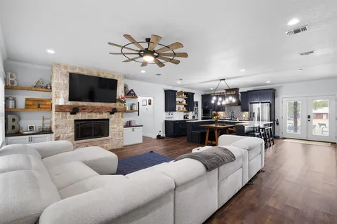 a kitchen with stainless steel appliances granite countertop a stove a refrigerator a sink dishwasher a dining table and chairs with wooden floor