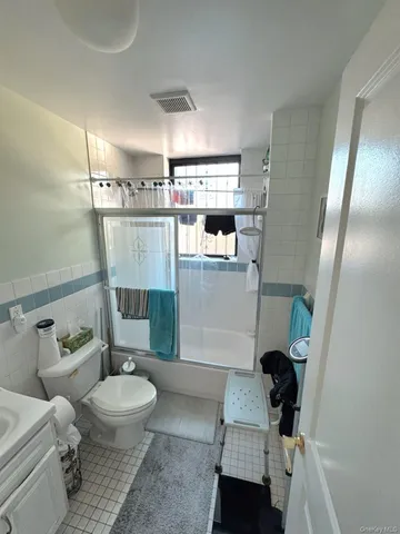 an empty room with chandelier fan and windows