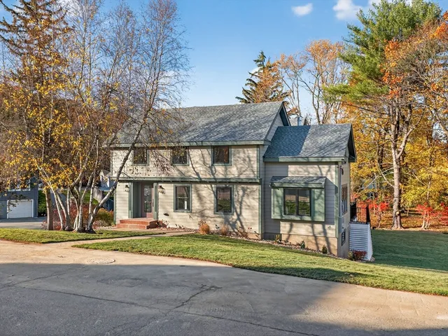 a front view of a house with a garden and trees