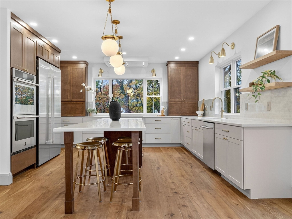 9 Norfolk Road Winchester, MA 01890 - Photo 14 of 42 a kitchen with stainless steel appliances kitchen island granite countertop a table chairs sink and cabinets
