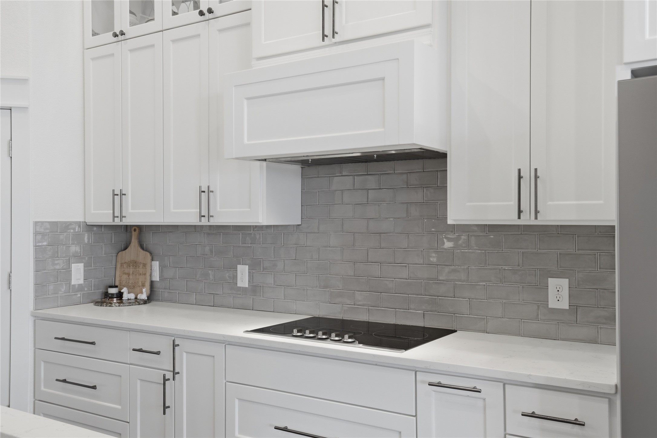 133 Greg Lane Jarrell, TX 76537 - Photo 10 of 24 Modern kitchen featuring white shaker cabinetry, light-toned countertops, a gray subway tile backsplash, a built-in cooktop, and a coordinating range hood
