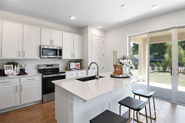 a kitchen with stainless steel appliances a stove a sink a microwave a dining table and chairs