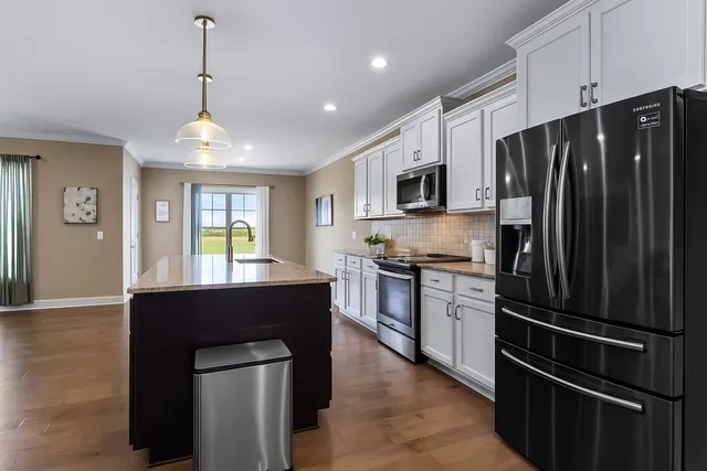 a kitchen with kitchen island granite countertop stainless steel appliances a sink a refrigerator a stove a microwave and island