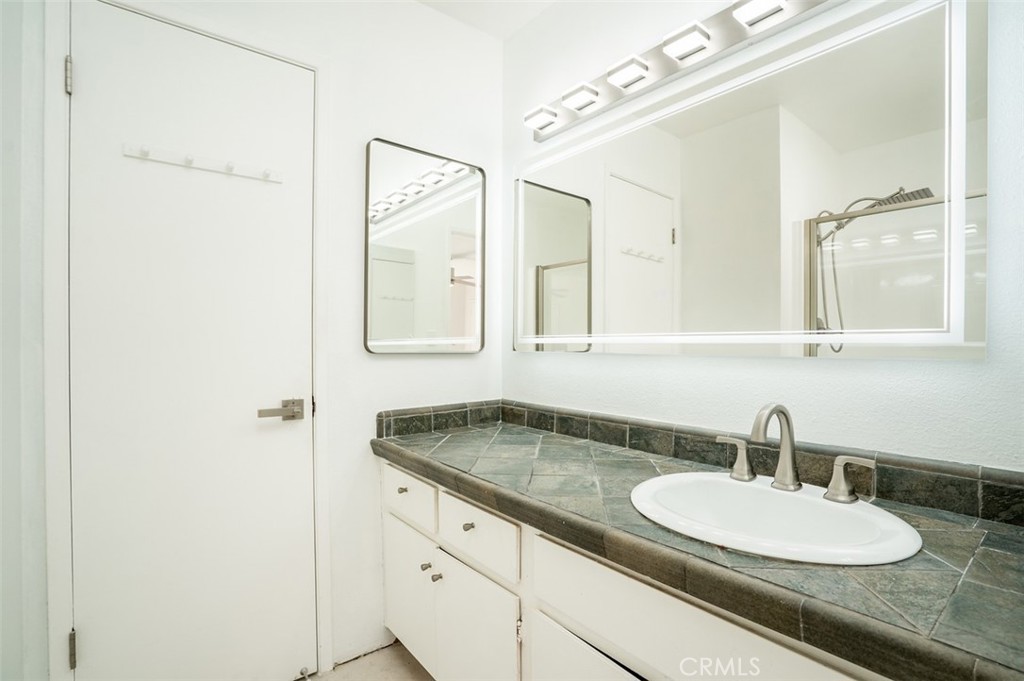 16734 Algonquin Street, Unit 6 Huntington Beach, CA 92649 - Photo 19 of 27 a bathroom with a granite countertop sink and a mirror