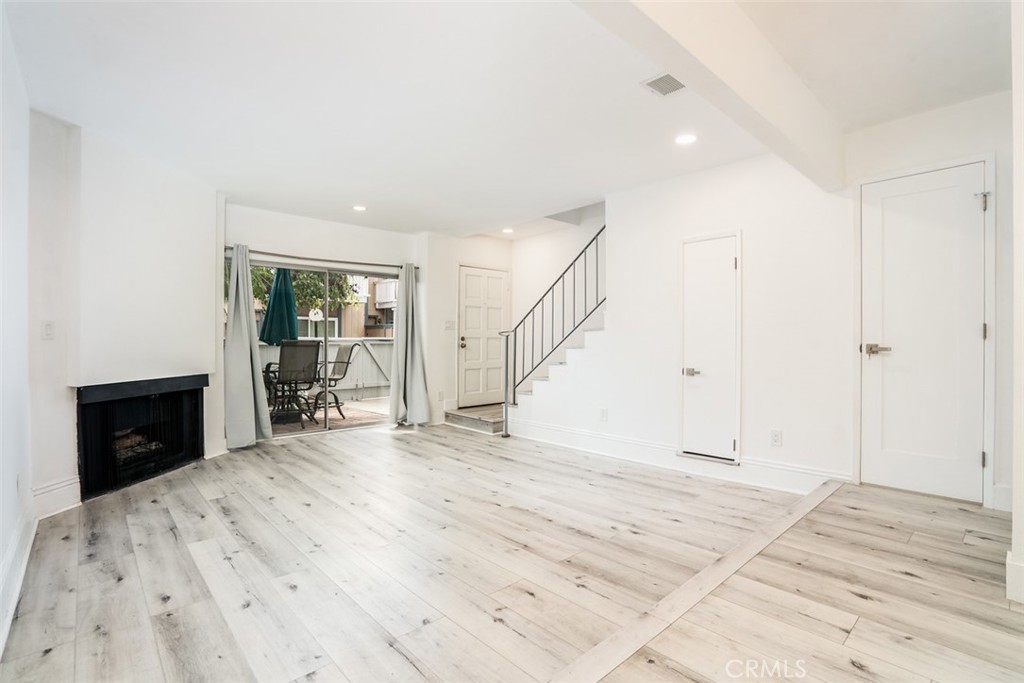 16734 Algonquin Street, Unit 6 Huntington Beach, CA 92649 - Photo 7 of 27 a view of an empty room with wooden floor and a fireplace