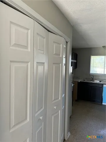 a view of an empty room with a window and a kitchen