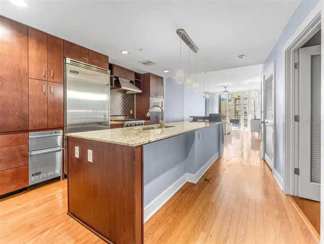 a kitchen with stainless steel appliances granite countertop a refrigerator a stove and a wooden floors