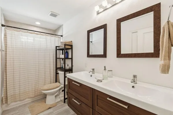 a bathroom with a double vanity sink toilet and shower
