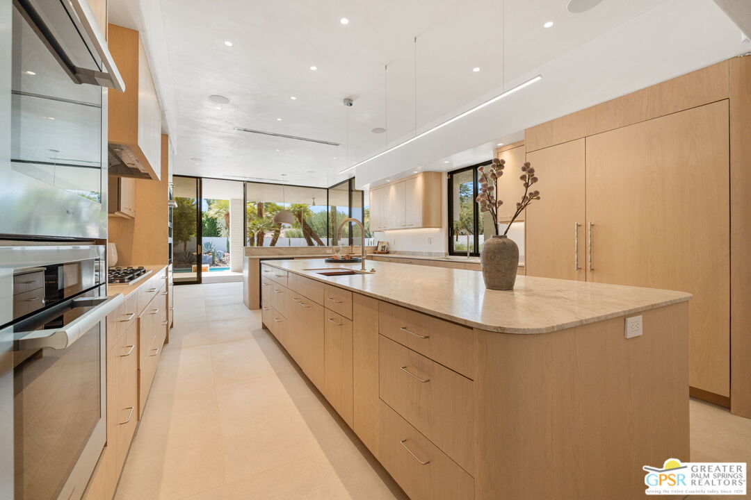 71000 Tamarisk Lane Rancho Mirage, CA 92270 - Photo 38 of 58 a large white kitchen with a sink and dishwasher a stove top oven with wooden floor
