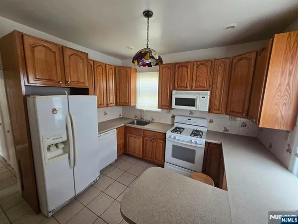 a kitchen with granite countertop a refrigerator a sink dishwasher a stove top oven a refrigerator and cabinets