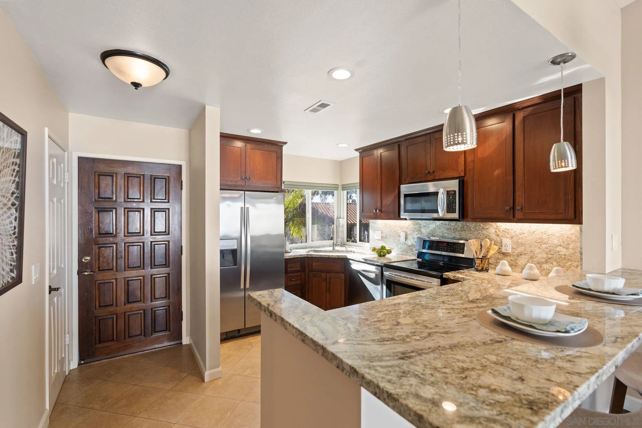 6922 Pear Tree Drive Carlsbad, CA 92011 - Photo 17 of 44 a kitchen with stainless steel appliances granite countertop a sink refrigerator and microwave