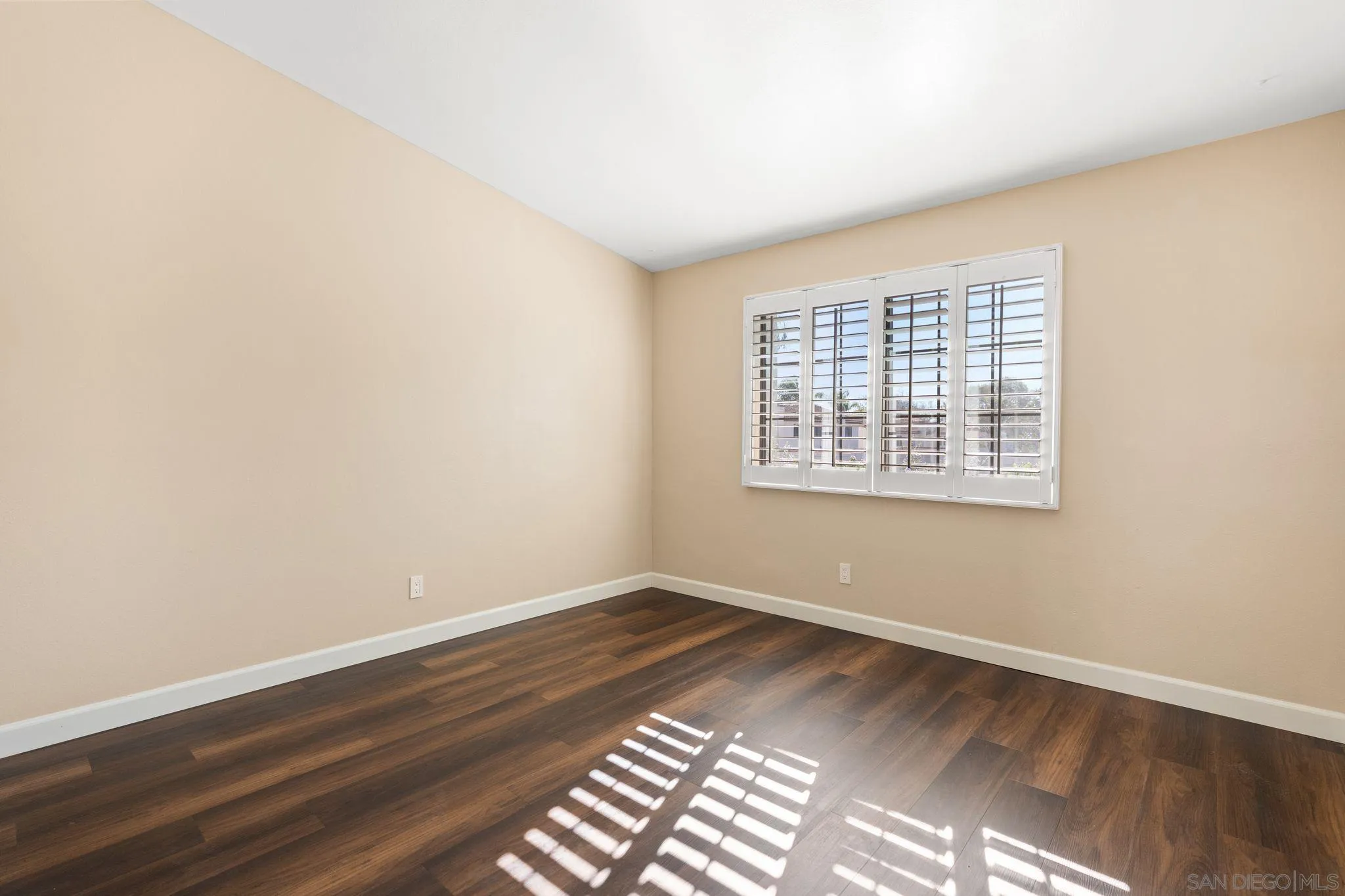 6922 Pear Tree Drive Carlsbad, CA 92011 - Photo 24 of 44 an empty room with wooden floor and windows