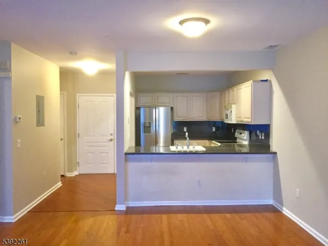a view of a kitchen with kitchen island a sink wooden floor and a large window