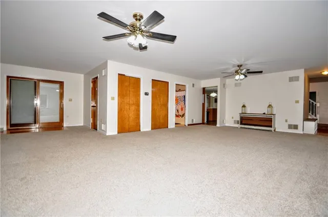a view of a livingroom with a chandelier fan and windows
