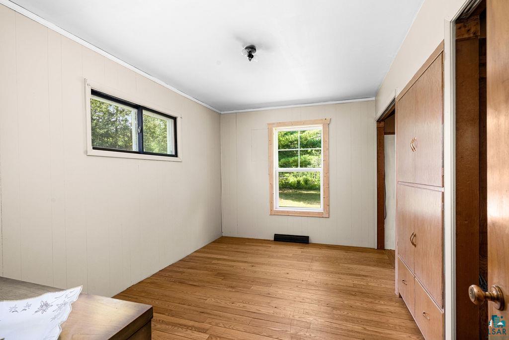 2592 Strandberg Road Barnum, MN 55707 - Photo 33 of 44 Light-filled room featuring wood-finish flooring, two windows with natural light, textured paneling, and an integrated wood-finish storage unit