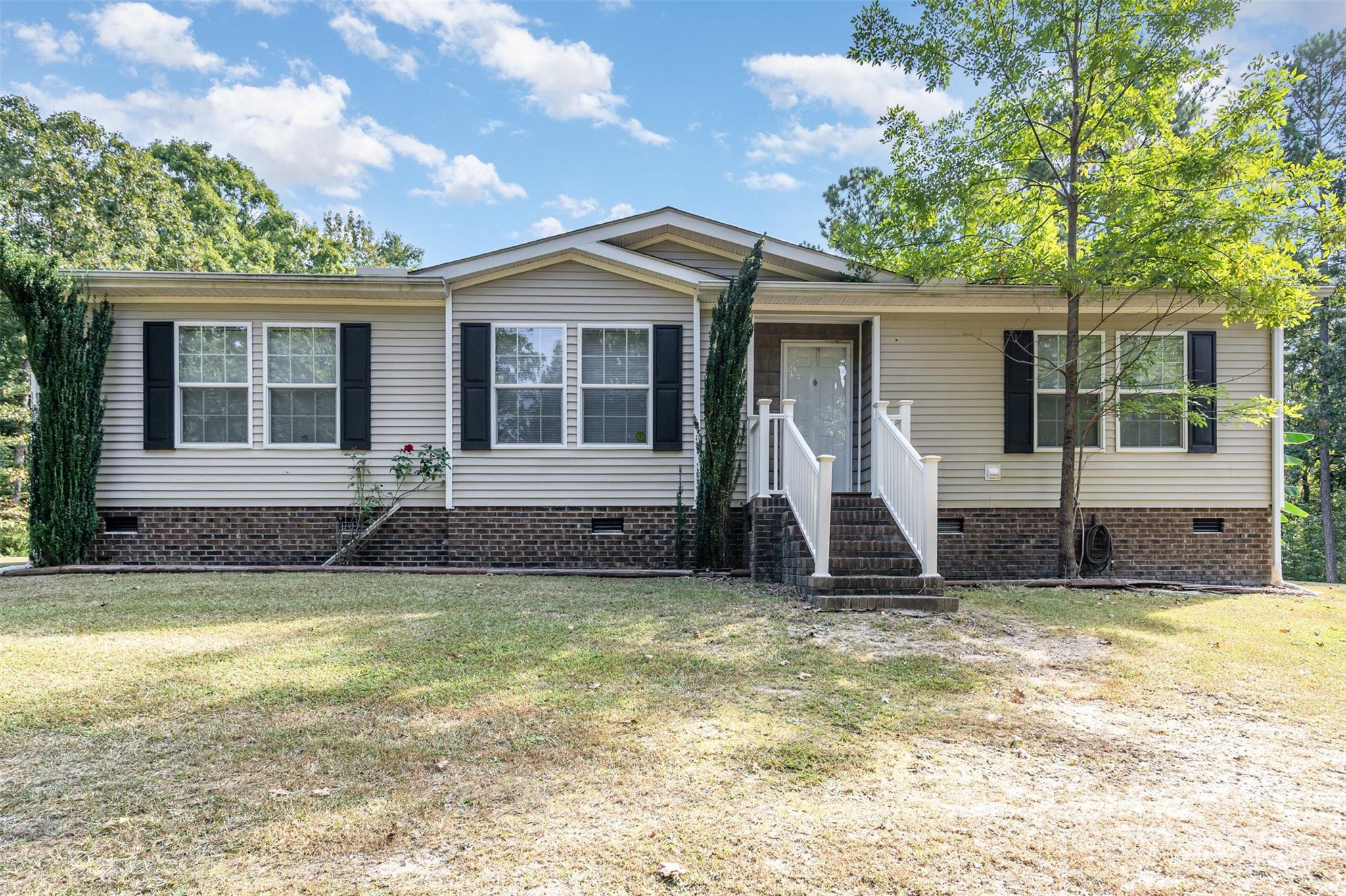 a view of a house with a yard and large tree