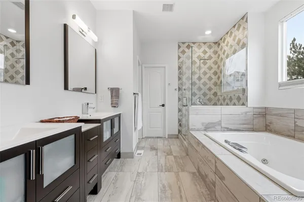 a spacious bathroom with a granite countertop sink mirror and a bathtub
