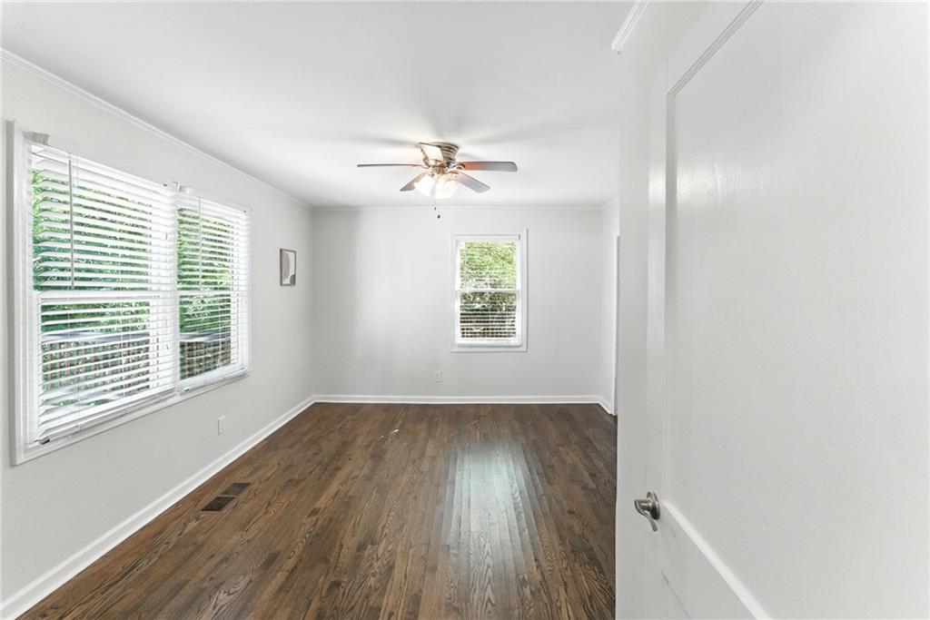 1411 Mercer Avenue Atlanta, GA 30337 - Photo 14 of 21 an empty room with wooden floor chandelier fan and windows