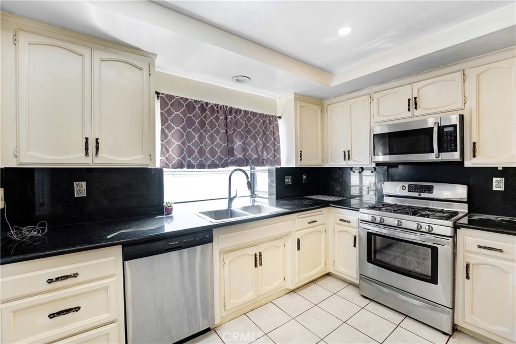 5514 Las Virgenes Road Calabasas, CA 91302 - Photo 7 of 20 a white kitchen with granite countertop a sink a stove a microwave and wooden cabinets
