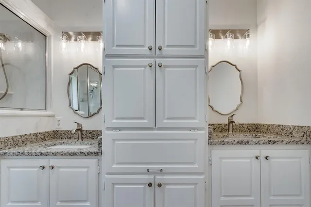 a bathroom with a granite countertop double vanity sink and a mirror