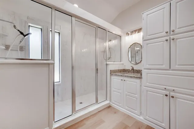 a bathroom with granite countertop a glass shower door and a sink