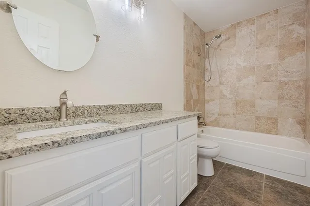 a bathroom with a granite countertop sink a toilet and bathtub