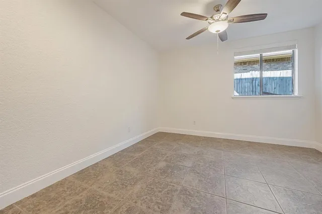 an empty room with a window and ceiling fan