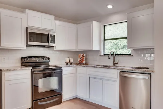 a kitchen with white cabinets stainless steel appliances and sink