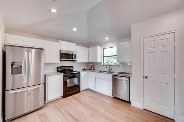 a kitchen with cabinets stainless steel appliances and wooden floor