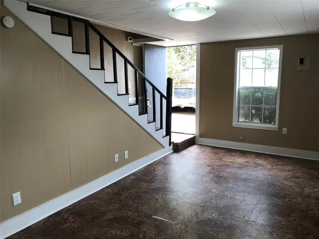 a view of an empty room with wooden floor and windows